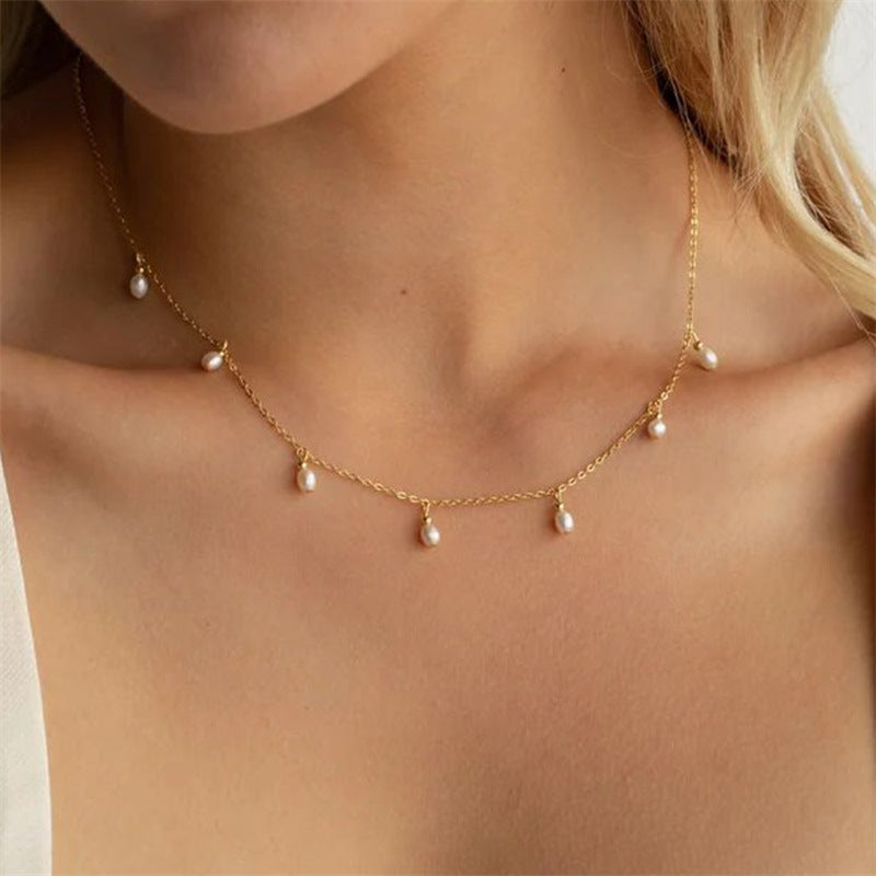 Goudkleurige ketting met kleine hangende pareltjes om de hals